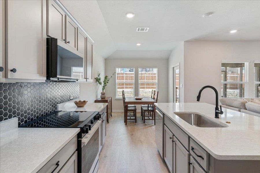 Kitchen featuring a sink, electric range oven, tasteful backsplash, stainless steel dishwasher, and visible vents