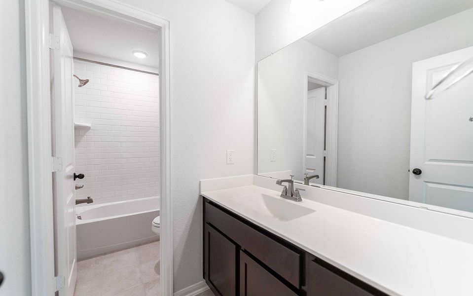 Bathroom featuring bathtub / shower combination, vanity, and light tile patterned floors Bathroom featuring bathtub / shower combination, vanity, and light tile patterned floors