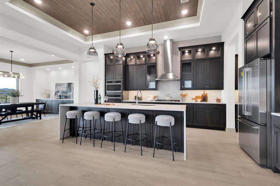 Kitchen with backsplash, decorative light fixtures, a breakfast bar area, high end fridge, and wooden ceiling