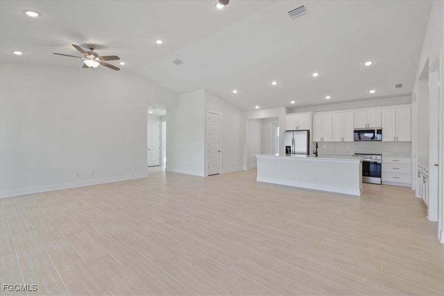 Unfurnished living room with recessed lighting, wood finish floors, a ceiling fan, and lofted ceiling