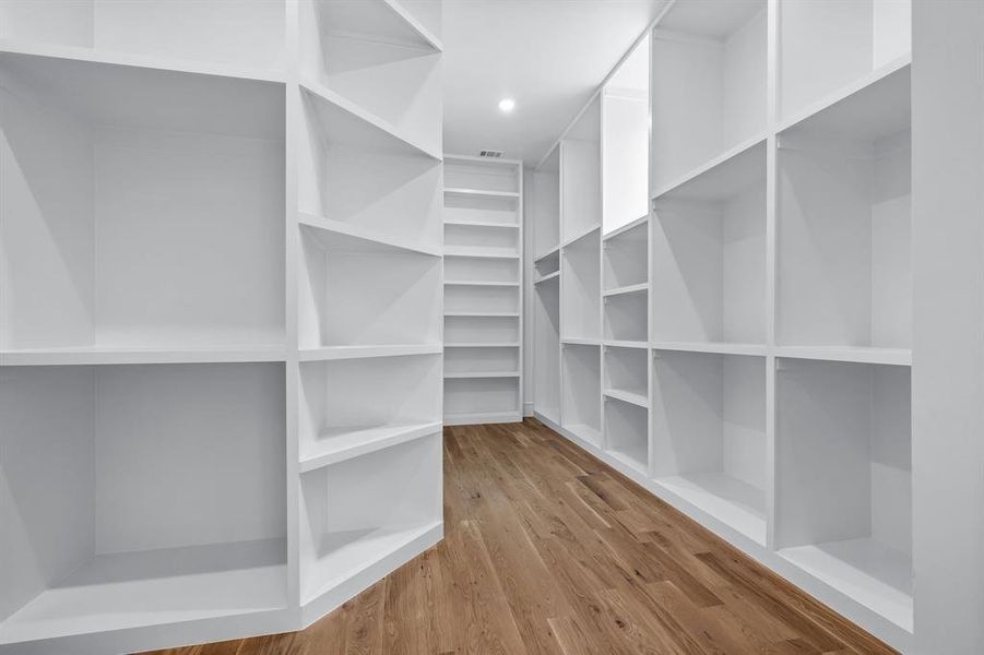 Spacious closet with light hardwood / wood-style flooring