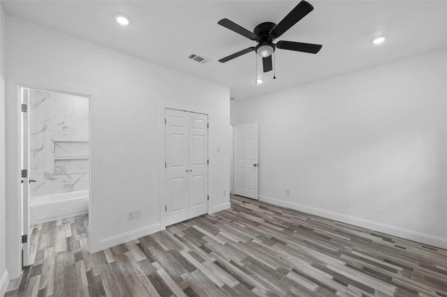 Unfurnished bedroom featuring ensuite bathroom, light wood-style floors, recessed lighting, ceiling fan, and a closet
