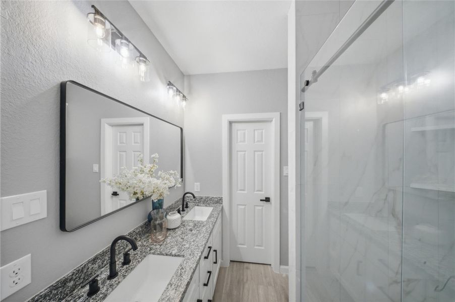 Luxurious primary bathroom featuring a sleek shower and elegant double vanity.