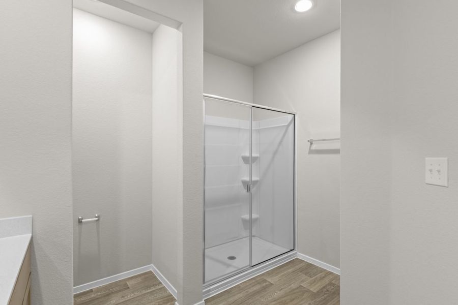 Image of a primary bathroom with beige walls, light brown wood-look flooring, and a standing shower Image of a primary bathroom with beige walls, light brown wood-look flooring, and a standing shower