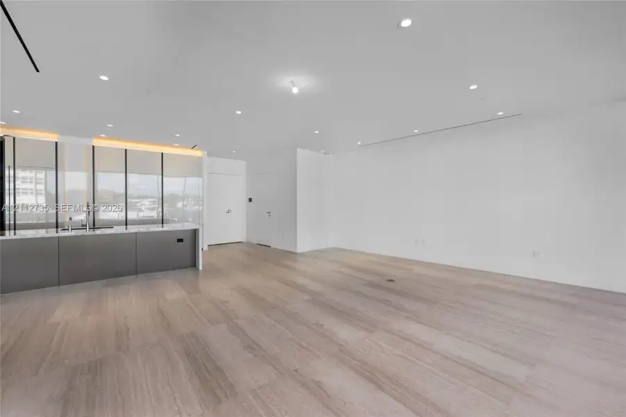 Interior space featuring wood-finish flooring, recessed ceiling lighting, and a kitchen island with stone countertop