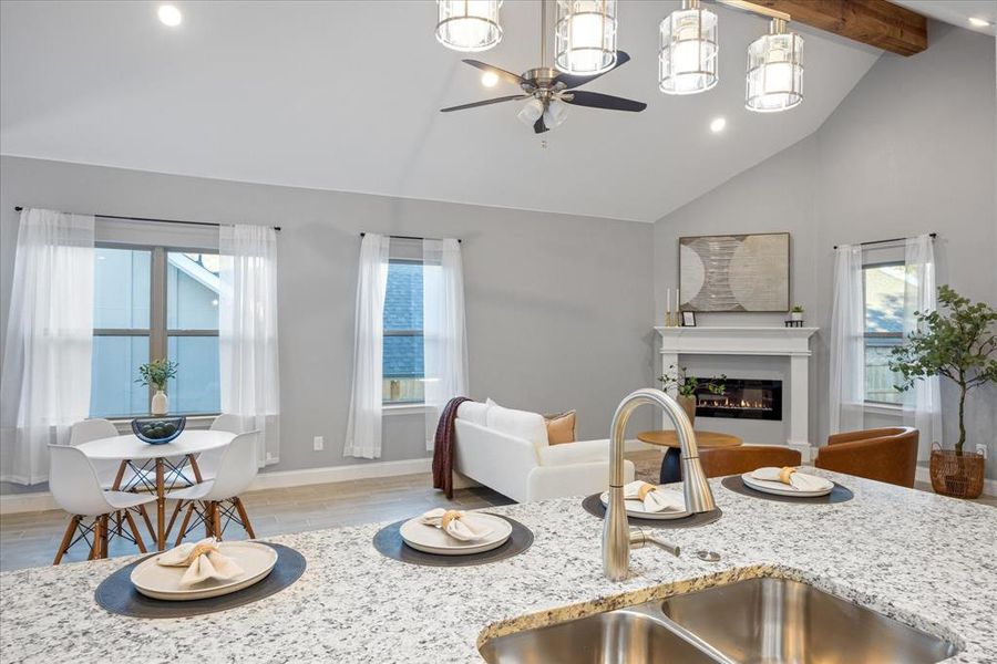 Kitchen with sink, vaulted ceiling with beams, light stone countertops, and plenty of natural light