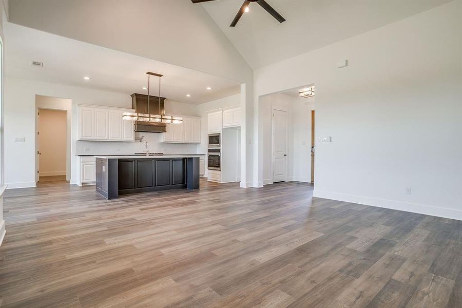 Unfurnished living room featuring ceiling fan, light wood finished floors, recessed lighting, and lofted ceiling Unfurnished living room featuring ceiling fan, light wood finished floors, recessed lighting, and lofted ceiling