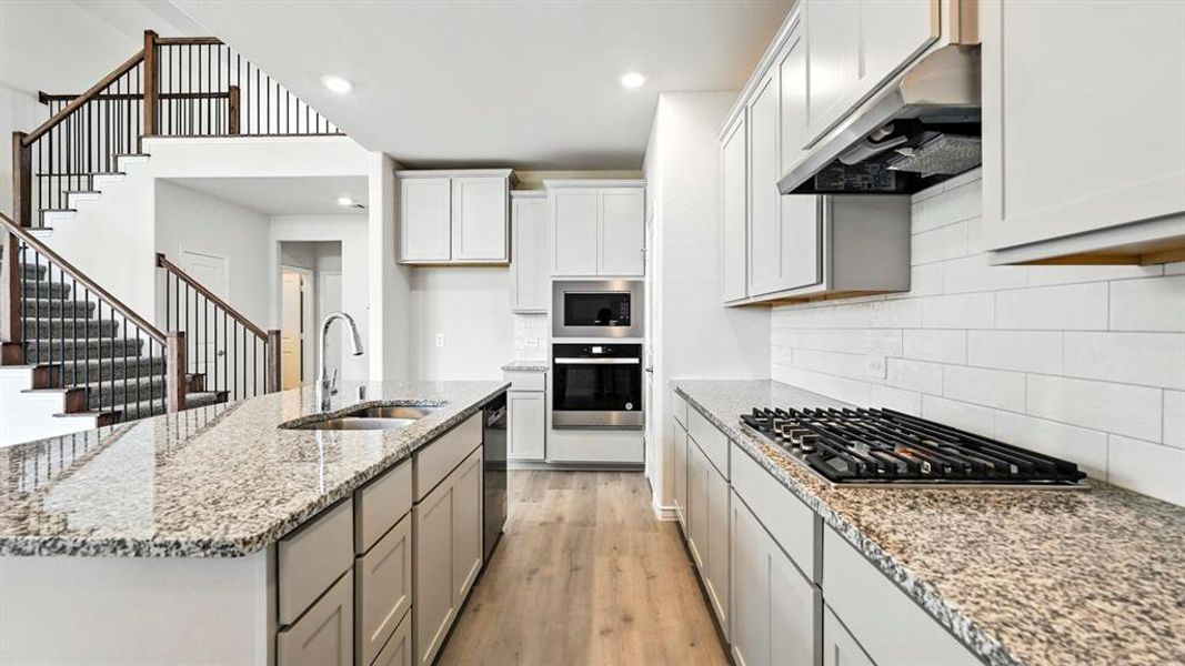 Kitchen featuring an expansive island with a stainless steel sink and granite countertops