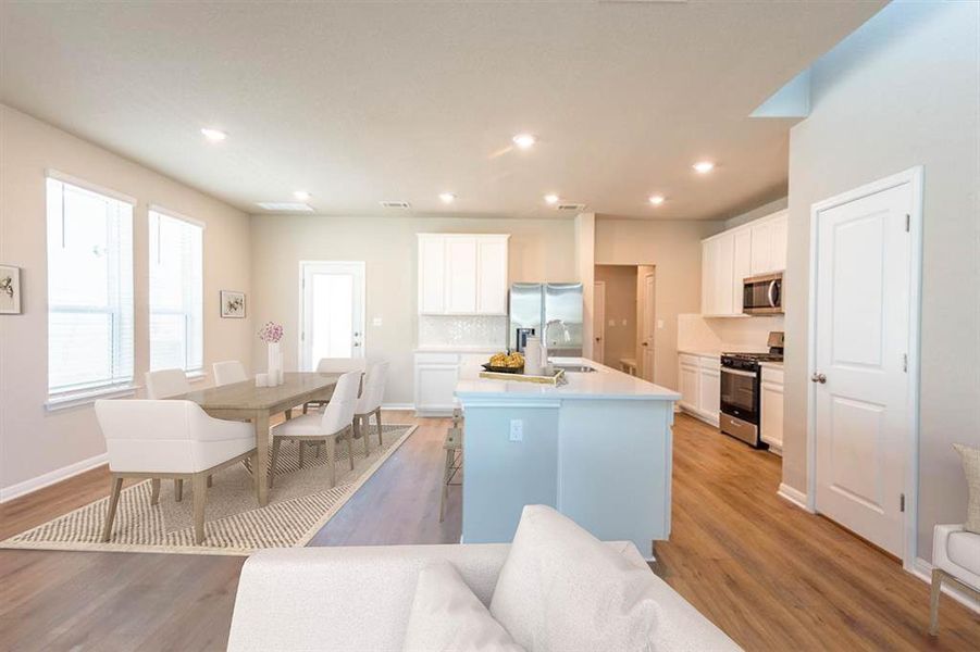 Virtually staged dining area = bak door leads to covered patio.  Shows Kitchen and some appliances.