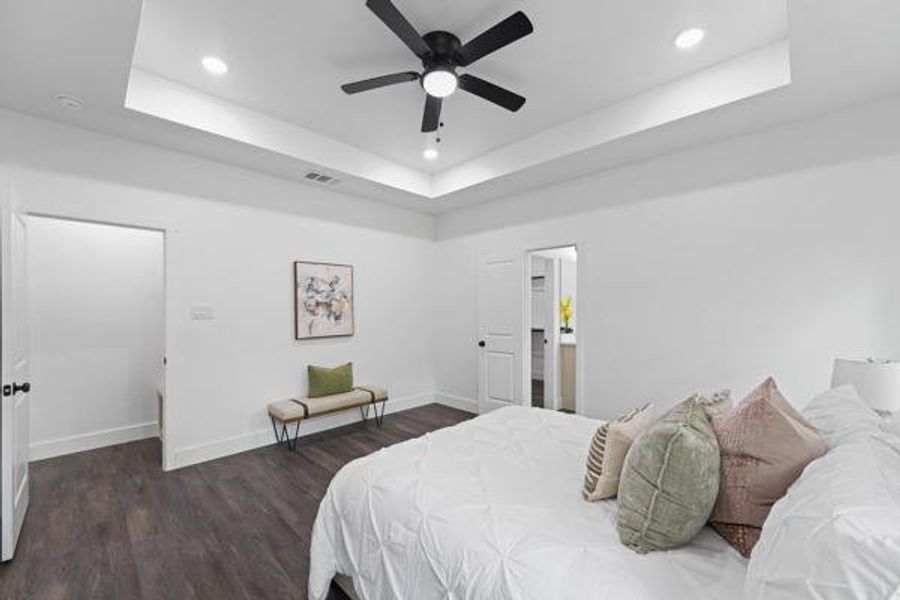 Spacious room featuring tray ceiling with recessed lighting and a ceiling fan, dark wood-finish flooring, and crisp white walls Spacious room featuring tray ceiling with recessed lighting and a ceiling fan, dark wood-finish flooring, and crisp white walls