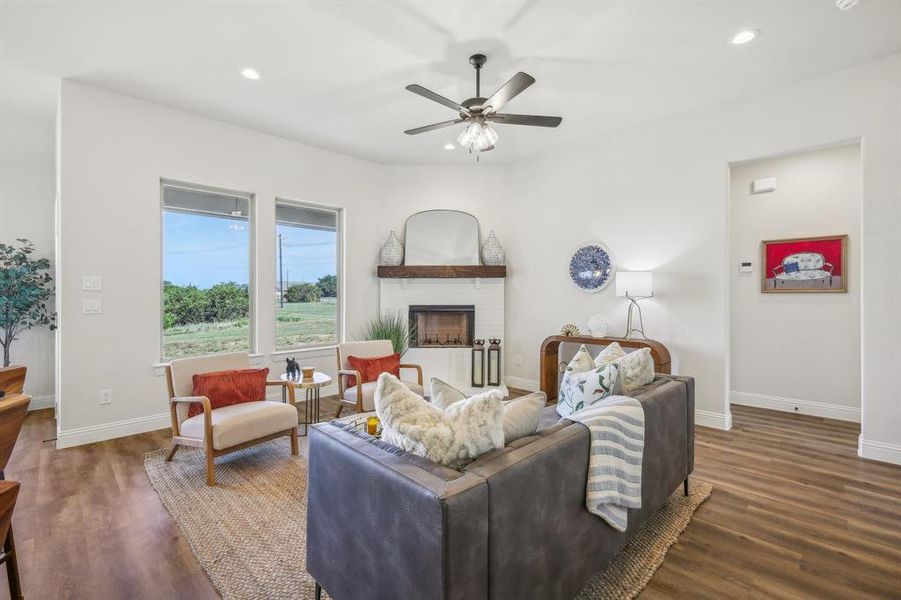 Living room with ceiling fan, a brick fireplace, and hardwood / wood-style flooring