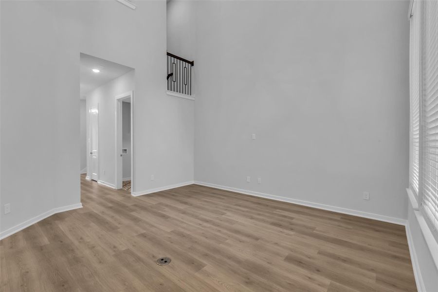 Family room with tall ceilings open wrought iron railing on the staircase.