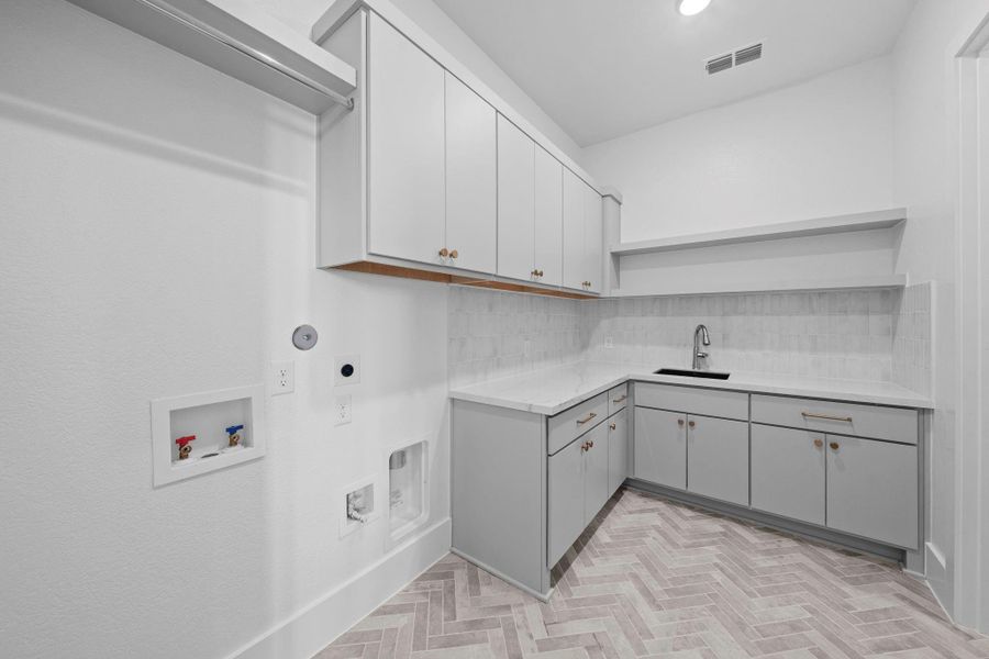 Dedicated utility room with custom cabinetry, generous workspace, and functional design.