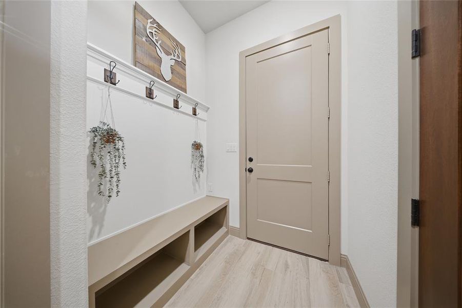 Built-in mudroom bench with cubby storage, featuring four wall-mounted hooks and a decorative top trim