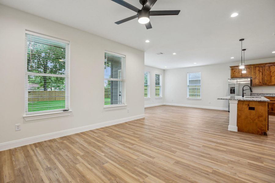 Living room with light wood-style vinyl flooring, baseboards, recessed lighting, and ceiling fan