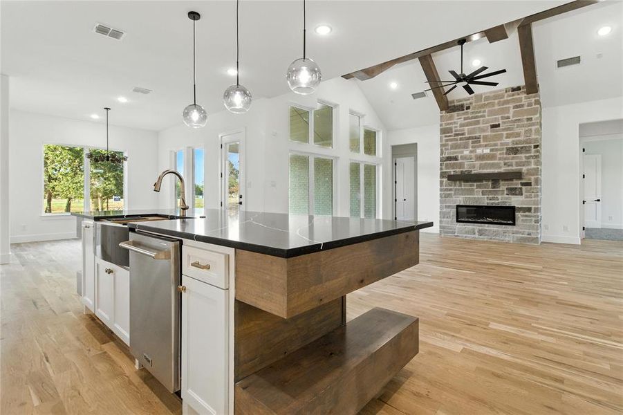 Kitchen featuring a stone fireplace, light wood-type flooring, white cabinets, open floor plan, and dishwasher Kitchen featuring a stone fireplace, light wood-type flooring, white cabinets, open floor plan, and dishwasher