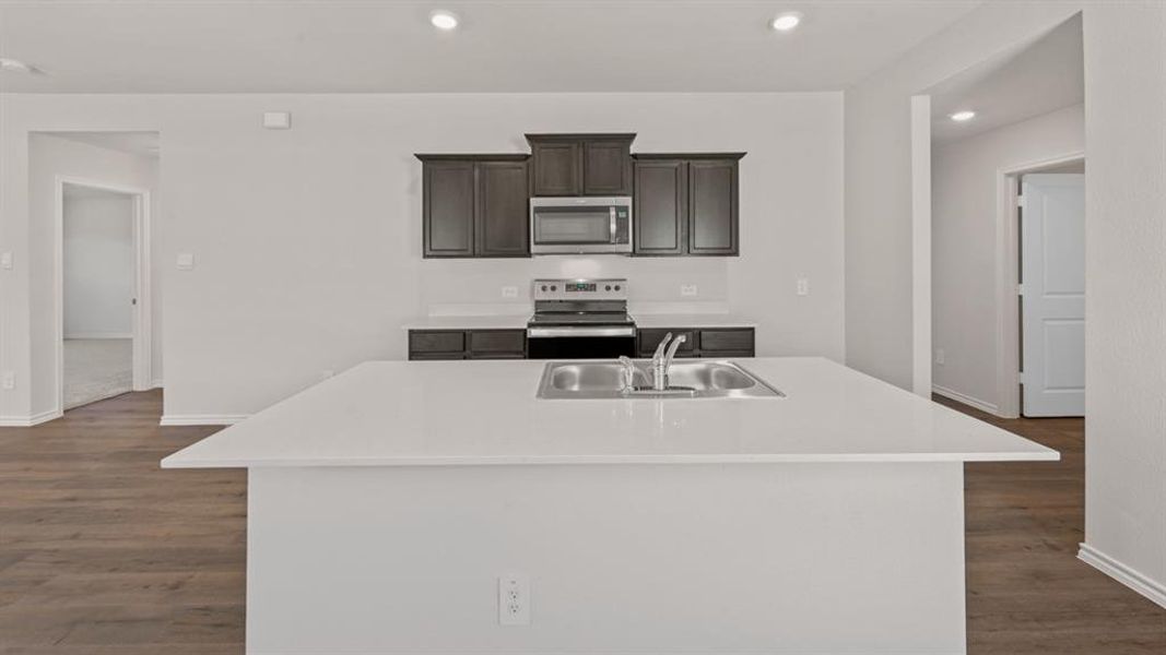 Kitchen featuring a large central island with an undermount double-basin stainless steel sink and white countertops