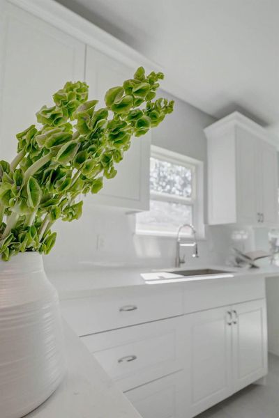 Beautifully designed kitchen boasting white cabinets, quartz counters, and generous natural light that creates an inviting and modern space