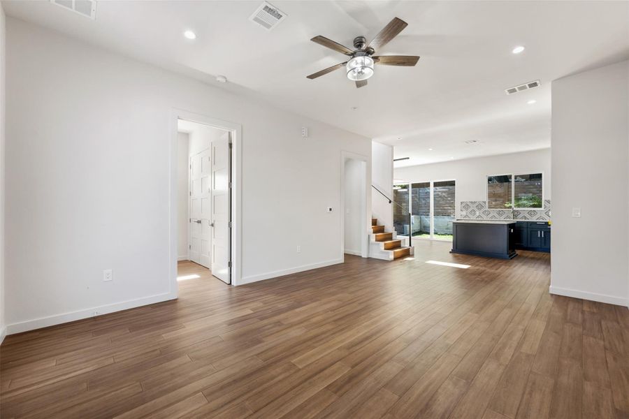 Unfurnished living room with stairs, recessed lighting, a ceiling fan, and dark wood finished floors