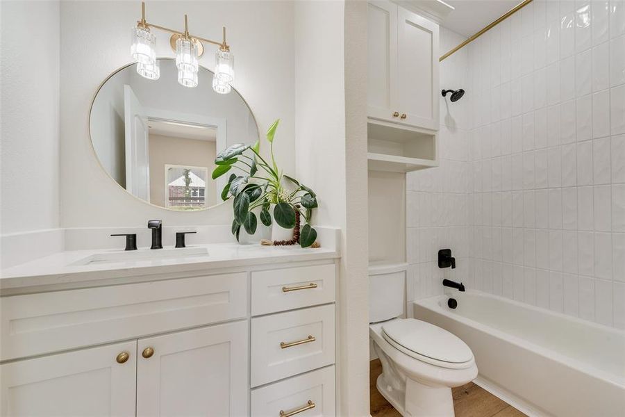 Bathroom featuring a white vanity with gold hardware, a round mirror, and a three-light fixture