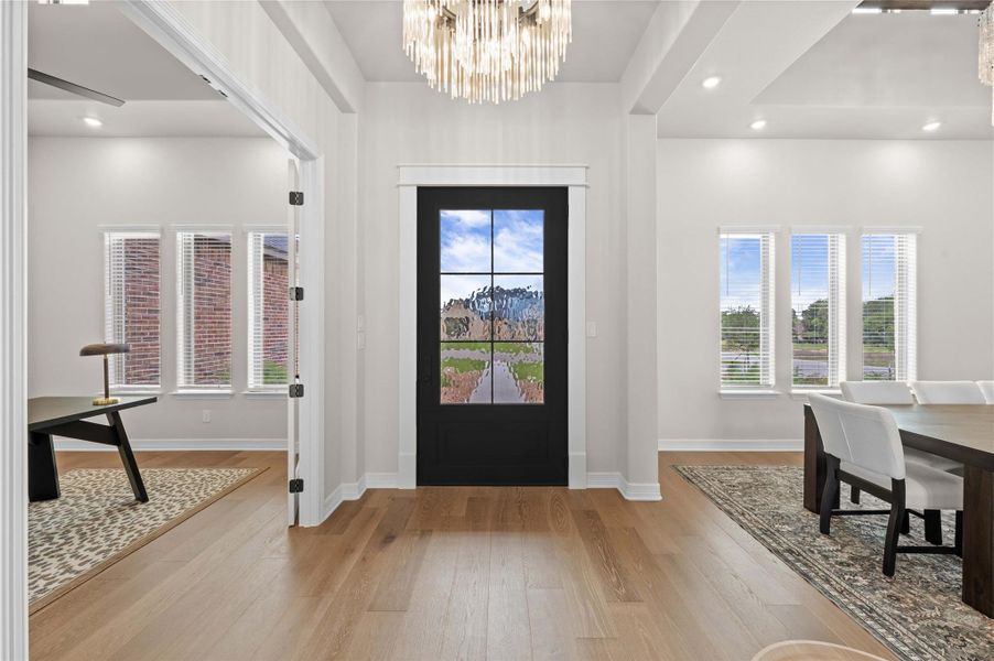 A striking entry door with frosted glass welcomes you into this home, showcasing light hardwood flooring and modern lighting. A striking entry door with frosted glass welcomes you into this home, showcasing light hardwood flooring and modern lighting.