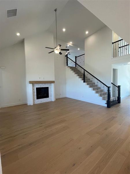 Unfurnished living room featuring a fireplace, a ceiling fan, light wood finished floors, recessed lighting, and lofted ceiling