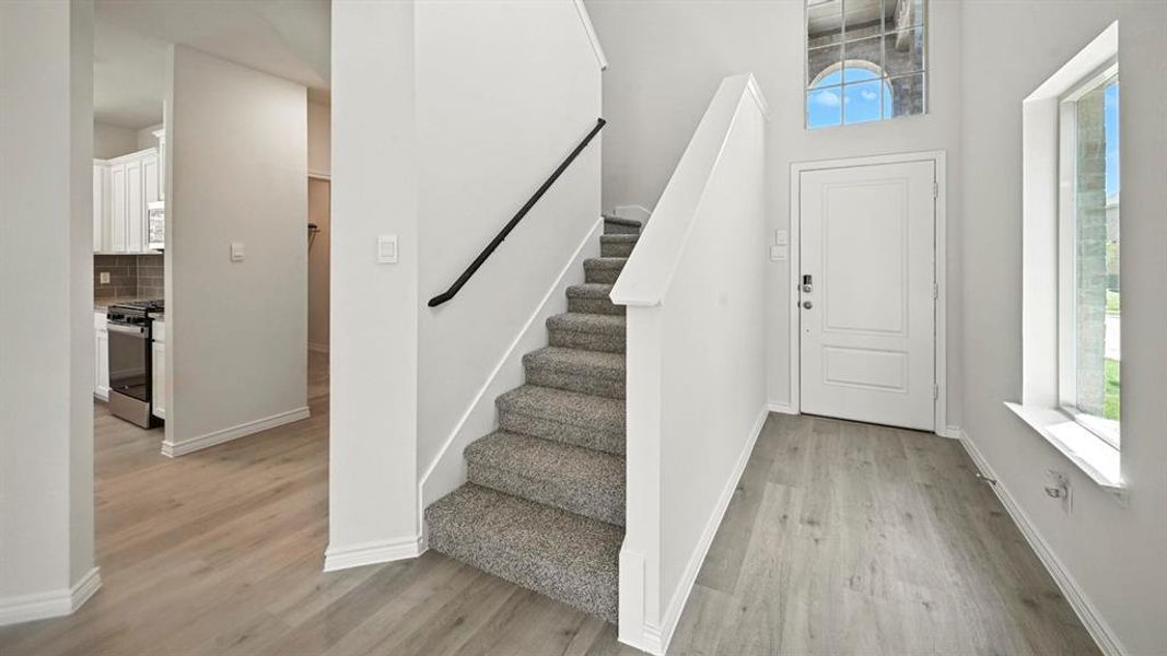 Foyer with stairs, light wood-style flooring, and a high ceiling