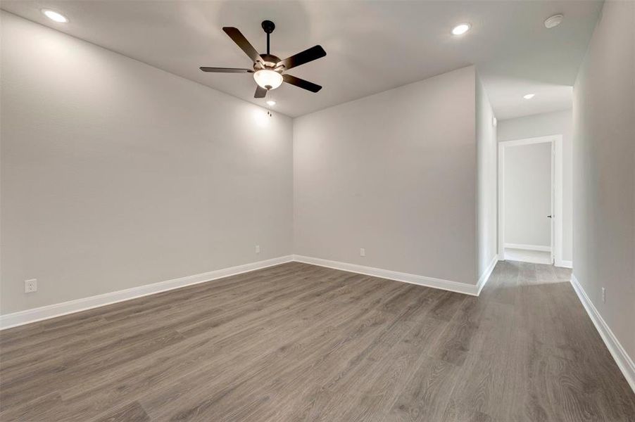 Spacious interior room featuring wood-finish flooring, recessed lighting, and a ceiling fan with integrated light