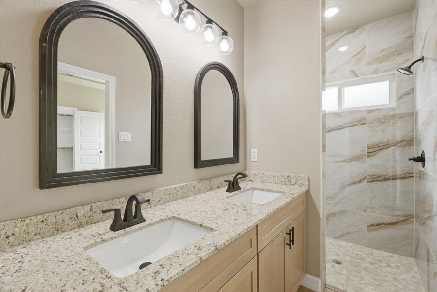Bathroom featuring double vanity and a marble finish shower