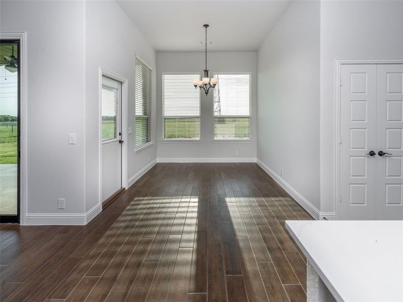Unfurnished dining area with dark wood-style flooring and a chandelier