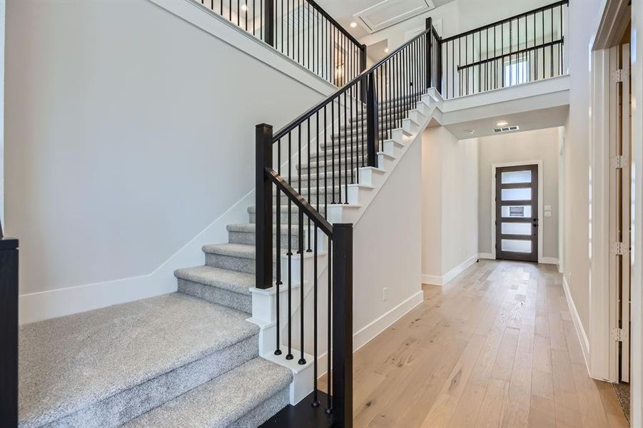 Entrance foyer with a high ceiling, baseboards, hardwood / wood-style flooring, and stairway Entrance foyer with a high ceiling, baseboards, hardwood / wood-style flooring, and stairway