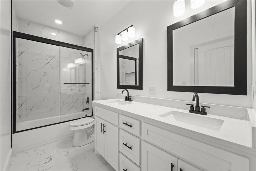 Full bathroom featuring toilet, vanity, and shower / bath combination with glass door