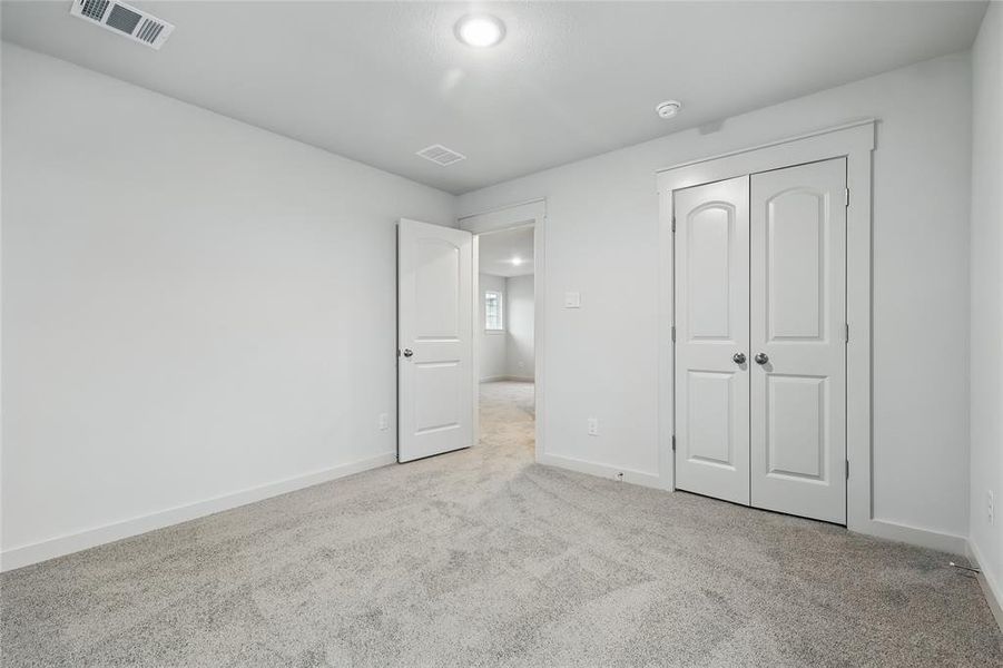 Unfurnished bedroom with light colored carpet and a closet