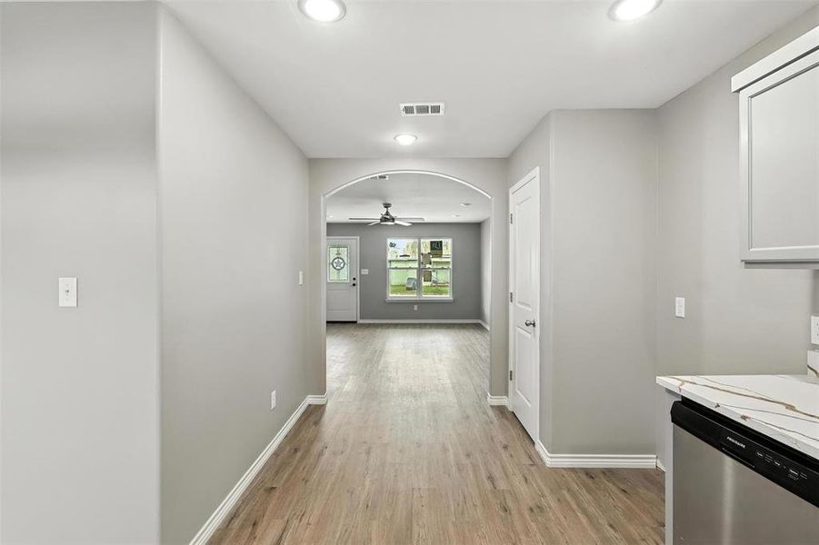 Hall featuring light wood finished floors, recessed lighting, and arched walkways Hall featuring light wood finished floors, recessed lighting, and arched walkways