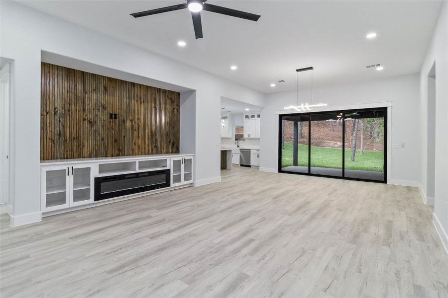 Unfurnished living room featuring recessed lighting, light wood-style flooring, a chandelier, and a ceiling fan