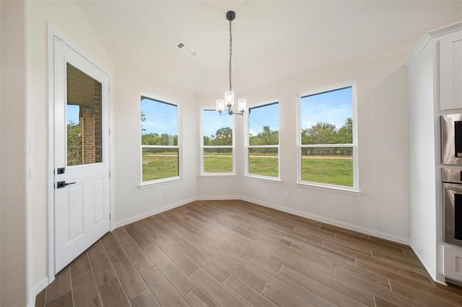 Unfurnished dining area featuring a chandelier, healthy amount of natural light, and dark wood-style flooring