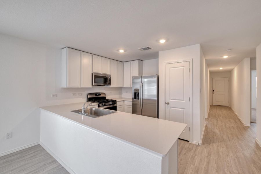 Kitchen featuring white cabinetry, stainless steel appliances, a gas range, and a breakfast bar with an undermount sink