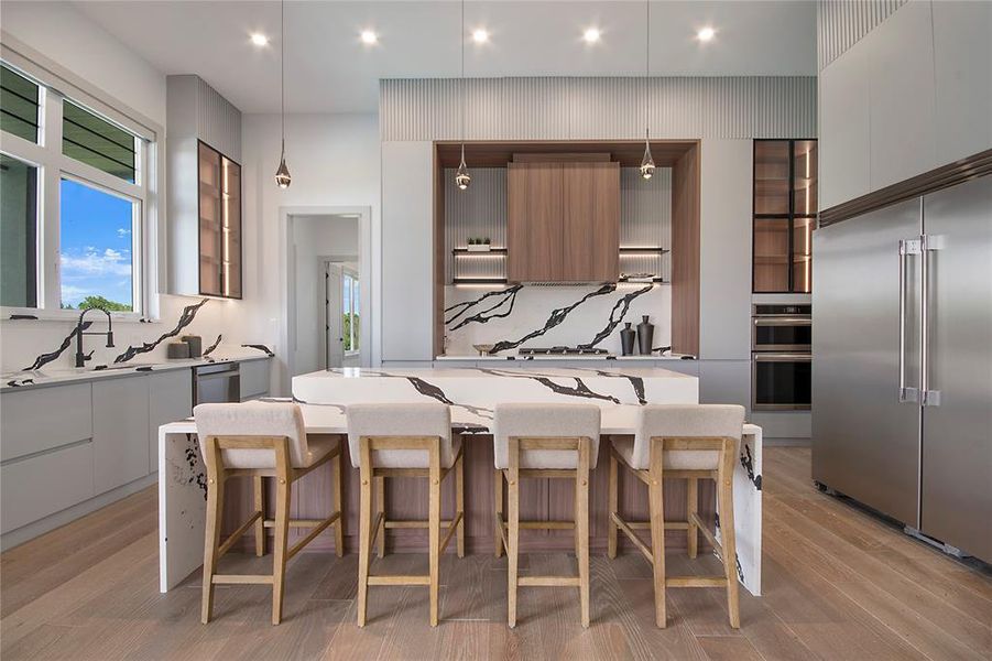 Kitchen featuring modern cabinets, appliances with stainless steel finishes, a kitchen breakfast bar, tasteful backsplash, and recessed lighting
