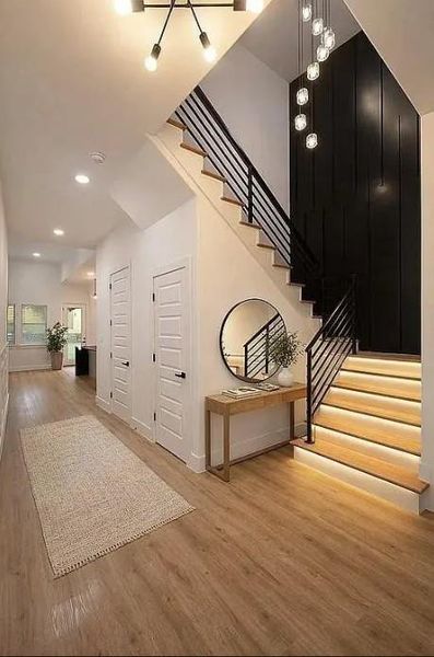 Staircase featuring wood-finish treads with integrated lighting, a black metal railing, and a black accent wall
