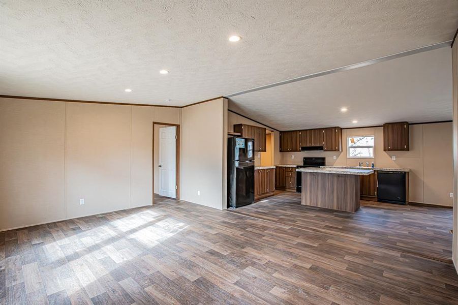 Kitchen featuring a kitchen island, a textured ceiling, black appliances, and dark hardwood / wood-style floors Kitchen featuring a kitchen island, a textured ceiling, black appliances, and dark hardwood / wood-style floors