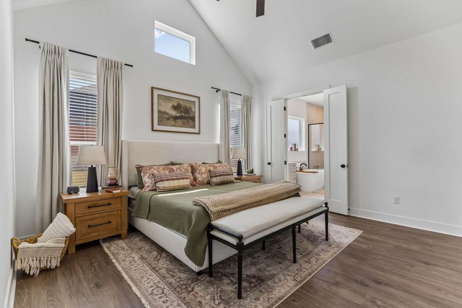 Vaulted ceilings and rich wood floors create a serene retreat with an adjacent bathroom.