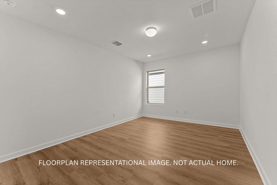 Recessed lighting and wood-look flooring enhance this flexible, neutral space.