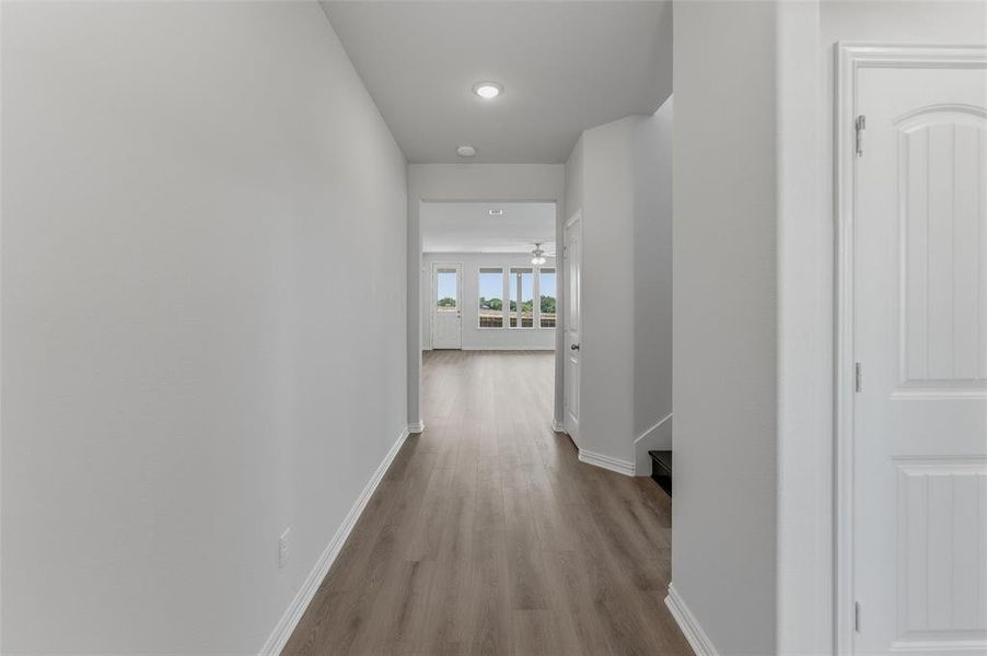 Hallway featuring wood-finish flooring, recessed lighting, and white baseboards