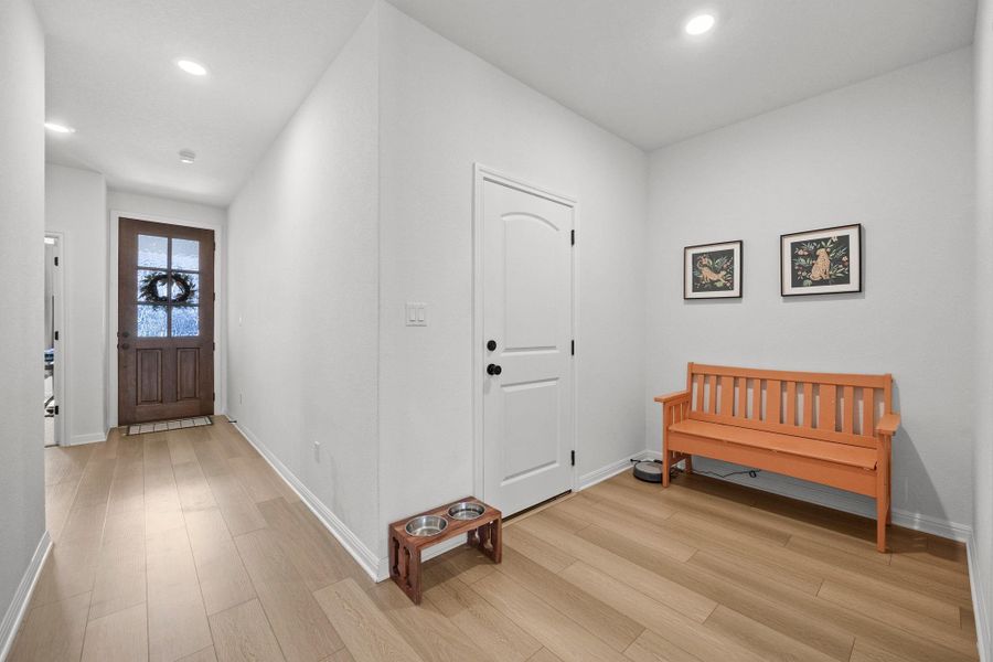 Entryway featuring a wood-panel door with frosted glass, light wood-finish flooring, recessed lighting, white trim, and a white interior door