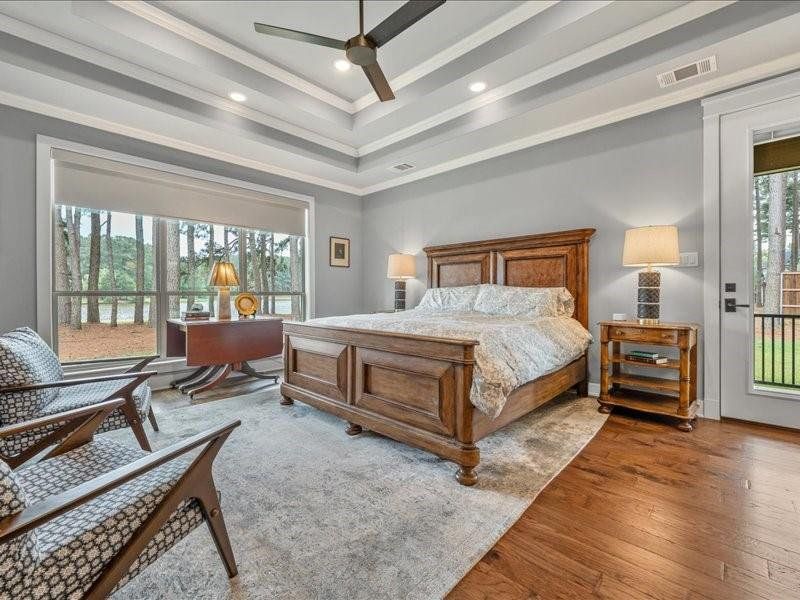 Spacious Primary Bedroom with incredible views of the lake.  The full moon rises on this side and you see it through the pines.  Side patio access for dogs or just to enjoy a quiet moment.  Auto shades.