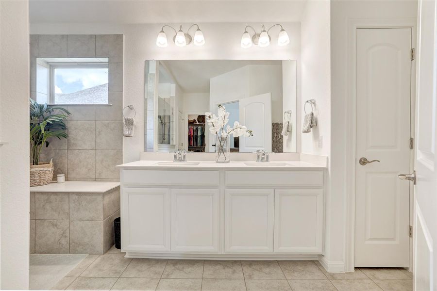 Full bathroom with double vanity, tile patterned floors, a spacious closet, and a walk in shower