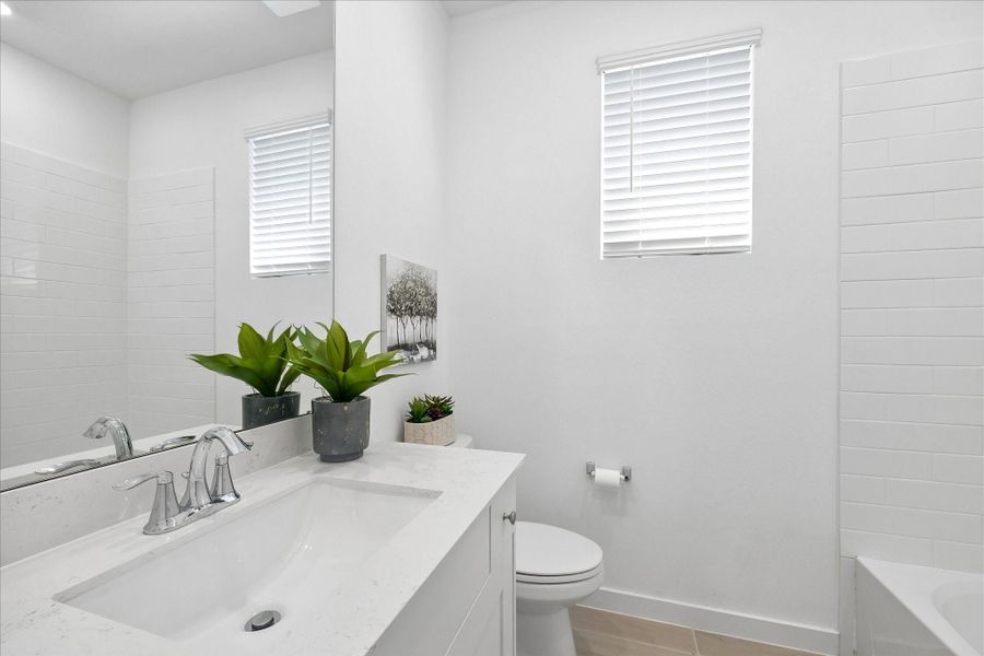 Crisp, clean finishes keep this full bath feeling fresh, with a quartz topped vanity, wood look tile flooring and a fully tiled tub and shower ready for guests or everyday routines.
