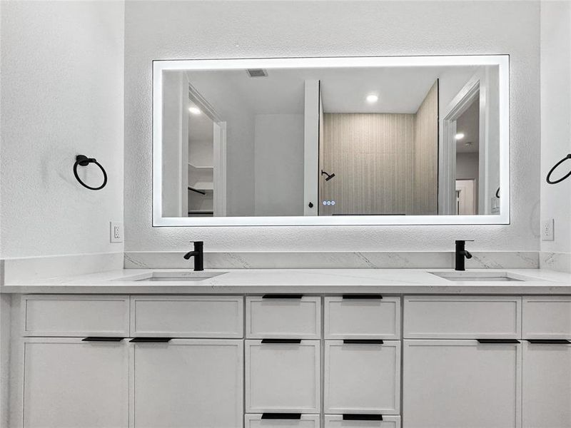 Bathroom featuring a textured wall and double vanity