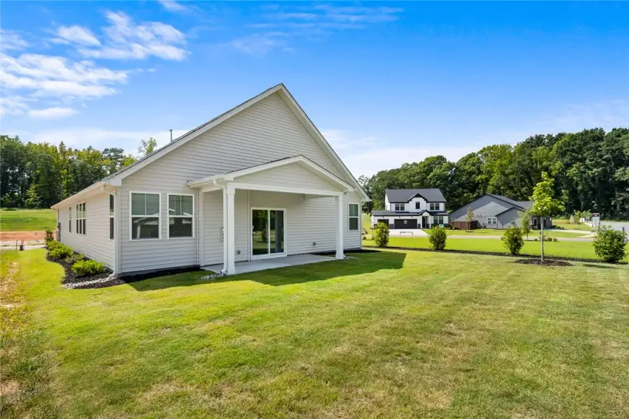 A spacious grassy lawn borders the covered back pa A spacious grassy lawn borders the covered back pa