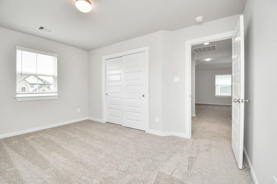 Generously sized secondary bedrooms featuring spacious closets, soft and inviting carpeting underfoot, large windows allowing plenty of natural light, and the added touch of privacy blinds for your personal retreat.